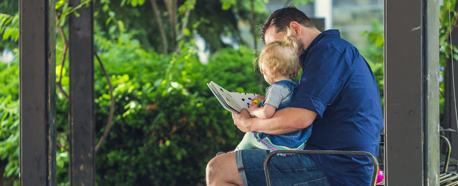 A dad is reading to his kid, helping the early development