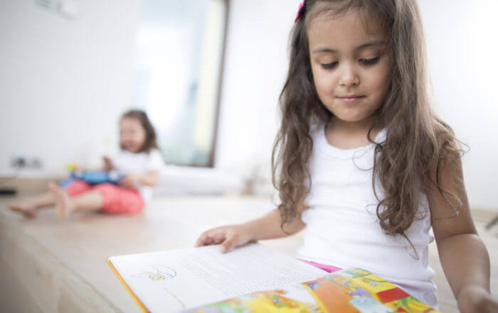 A girl is reading books picked by St Clare Group to develop the different brain areas of preschoolers such as problem-solving.